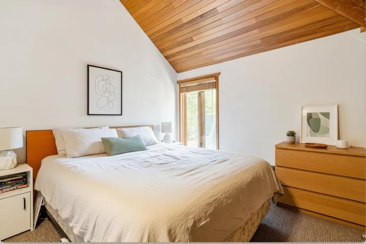 Carpeted bedroom featuring a vaulted wood ceiling - digitally staged