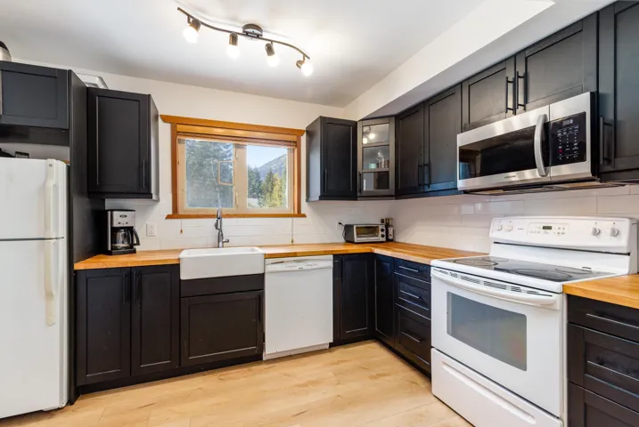 Kitchen featuring white appliances, butcher block counters, a sink, and tasteful backsplash