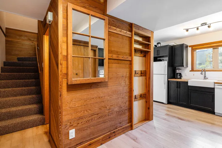 Kitchen featuring white appliances, a sink, dark cabinetry, light wood-style floors, and light countertops