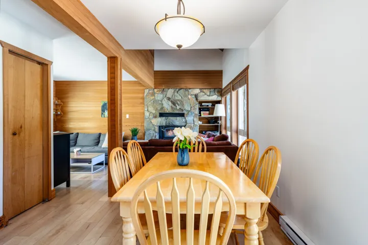 Dining area with a baseboard radiator, wood walls, light wood finished floors, and a stone fireplace
