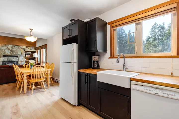 Kitchen with white appliances, wood counters, a sink, tasteful backsplash, and plenty of natural light
