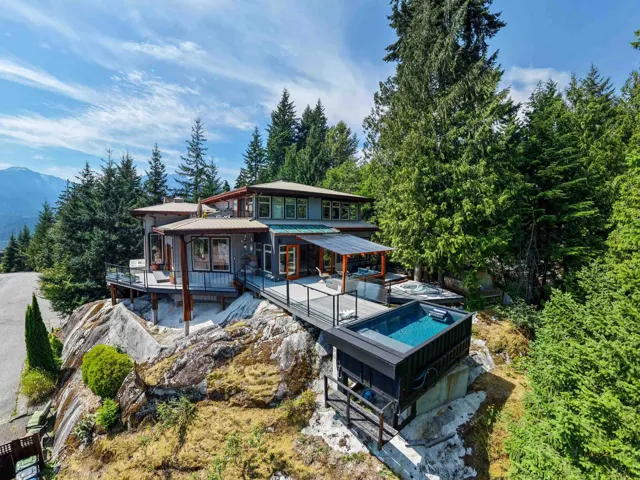 Contemporary multi-level residence featuring extensive decking, glass panel railings, and a separate plunge pool with a connected walkway