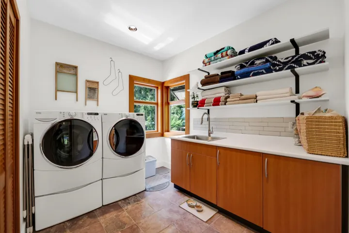 Functional laundry area featuring a built-in sink, white countertop, and light wood-finish cabinetry