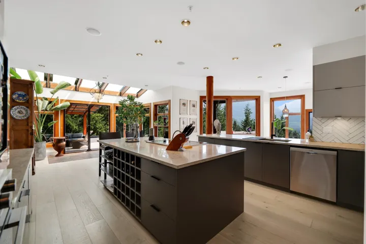 Contemporary kitchen featuring an island with integrated wine storage, light wood-finish flooring, recessed lighting, and stainless steel appliances