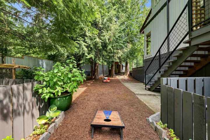 Expansive outdoor space featuring mature evergreen trees, a well-defined pathway, and a modern exterior staircase with black metal railings