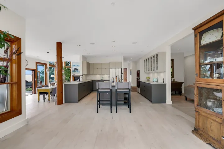 Spacious open-concept kitchen featuring light wood-finish flooring, two large kitchen islands with dark cabinetry, light countertops, and recessed lighting