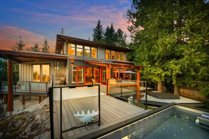 Multi-level outdoor living space featuring a contemporary pool, expansive composite decking, and glass panel railings