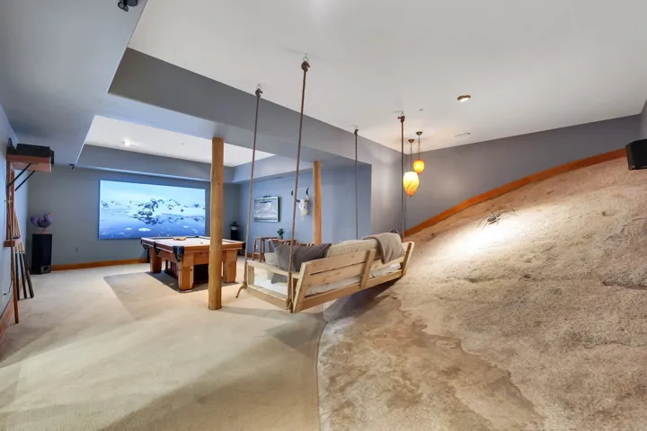 Recreation room featuring a built-in projection screen, recessed lighting, and support columns with a natural wood finish