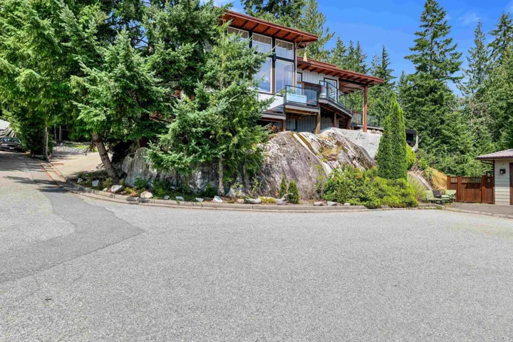 Property featuring a multi-level design with a prominent rock outcropping and extensive natural landscaping