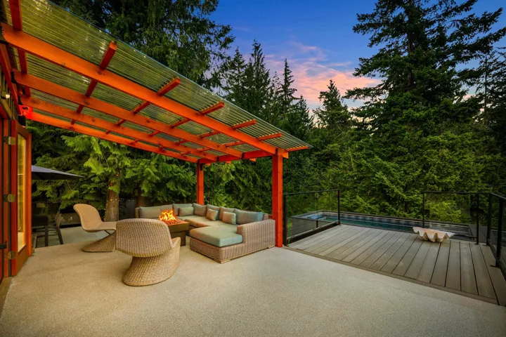 Expansive outdoor patio featuring a covered seating area with a clear corrugated roof, a separate deck area, and a built-in plunge pool