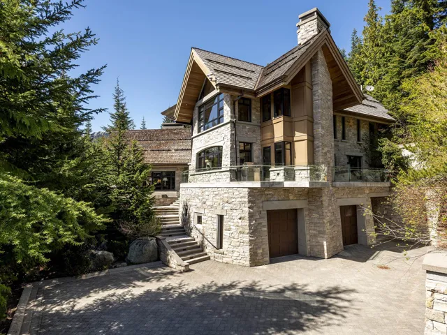 View of front of house featuring a balcony, stone siding, stairway, and decorative driveway