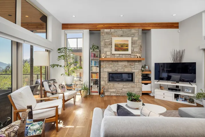 Living room featuring wood finished floors, a stone fireplace, and recessed lighting