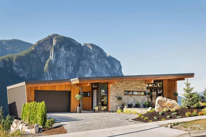Contemporary home featuring stone siding, decorative driveway, a mountain view, and an attached garage