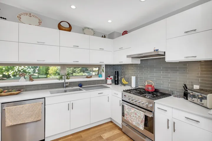 Kitchen with appliances with stainless steel finishes, decorative backsplash, light wood finished floors, light countertops, and recessed lighting