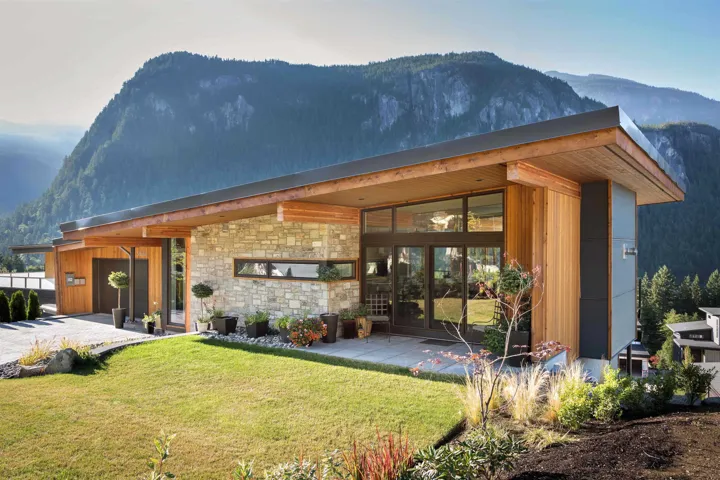 Rear view of property with a mountain view, a lawn, and stone siding