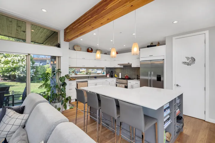 Kitchen with decorative backsplash, high quality appliances, white cabinets, wood finished floors, and light countertops