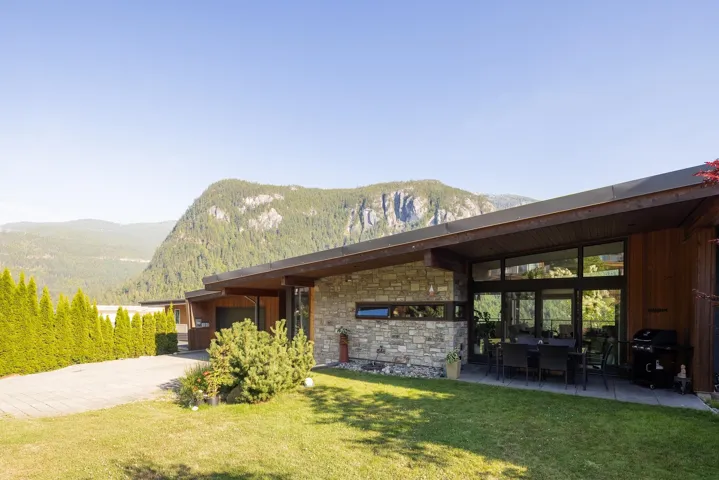View of home's community with a garage, a mountain view, a yard, driveway, and a patio