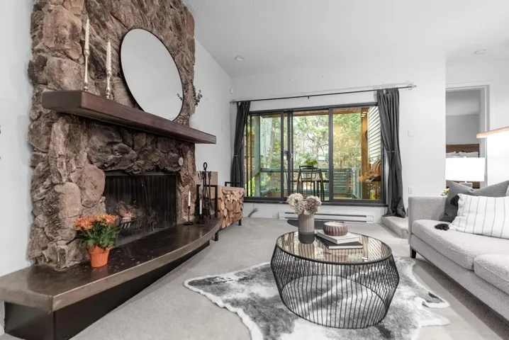 Living area with carpet flooring and a stone fireplace