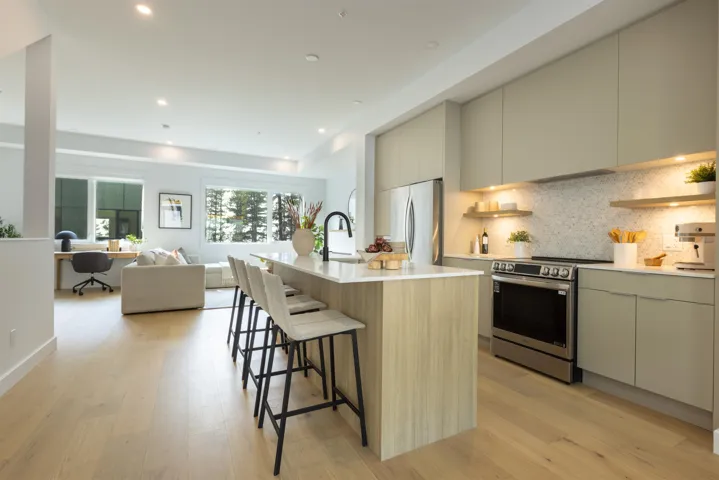 Kitchen with an office area, modern cabinets, appliances with stainless steel finishes, tasteful backsplash, and a kitchen breakfast bar