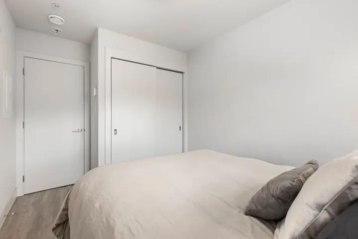 Bedroom with wood finished floors, a closet, and baseboards