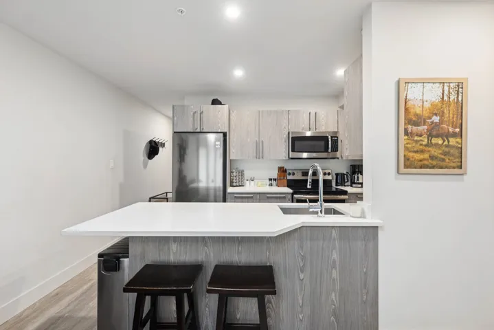 Kitchen featuring stainless steel appliances, a kitchen breakfast bar, a peninsula, light countertops, and light wood-style flooring