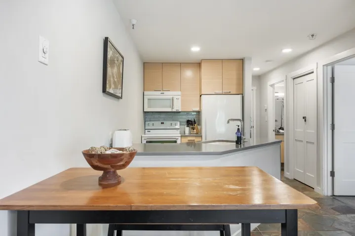 Kitchen with backsplash, white appliances, stone tile flooring, recessed lighting, and light brown cabinets