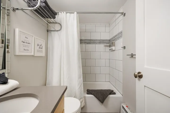Bathroom featuring shower / bathtub combination with curtain, vanity, and a baseboard radiator