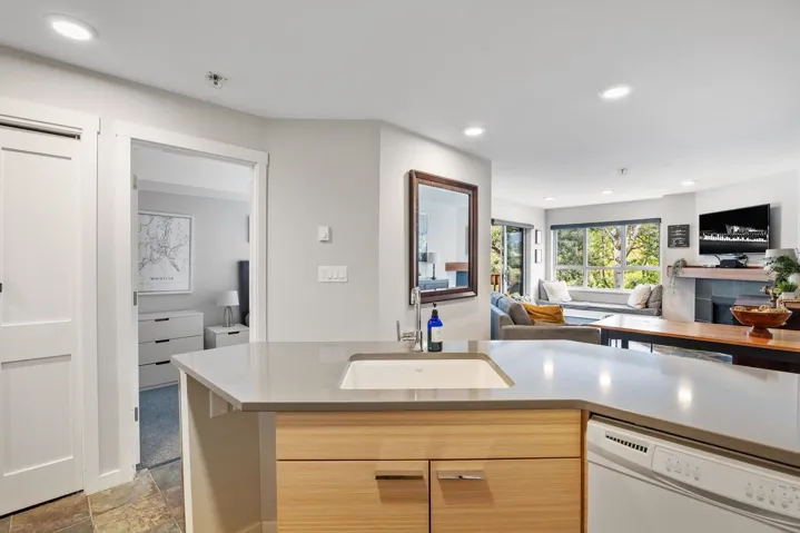 Kitchen featuring light brown cabinets, white dishwasher, open floor plan, modern cabinets, and recessed lighting