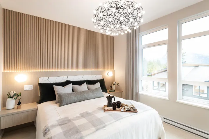 Bedroom with a baseboard radiator, wallpapered walls, an accent wall, and suspended lighting