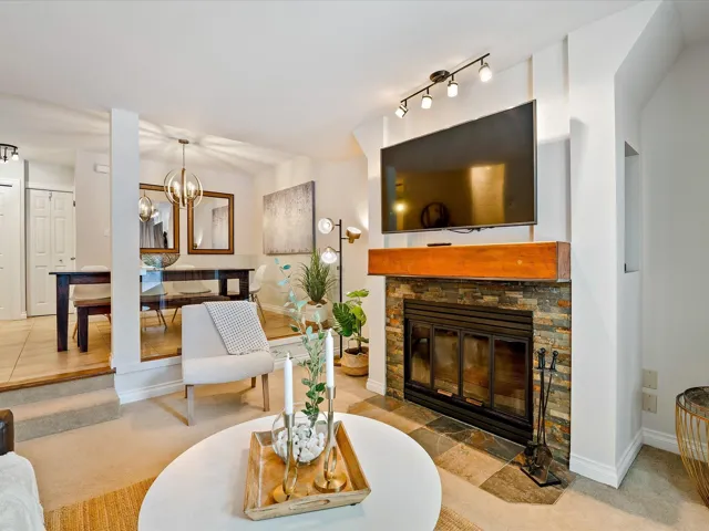 Carpeted living room with baseboards, a fireplace, and an inviting chandelier