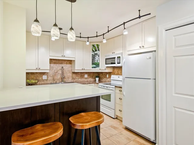 Kitchen featuring white cabinets, a sink, decorative backsplash, and white appliances
