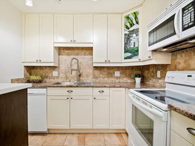 Kitchen featuring decorative backsplash, white cabinets, a sink, and white appliances