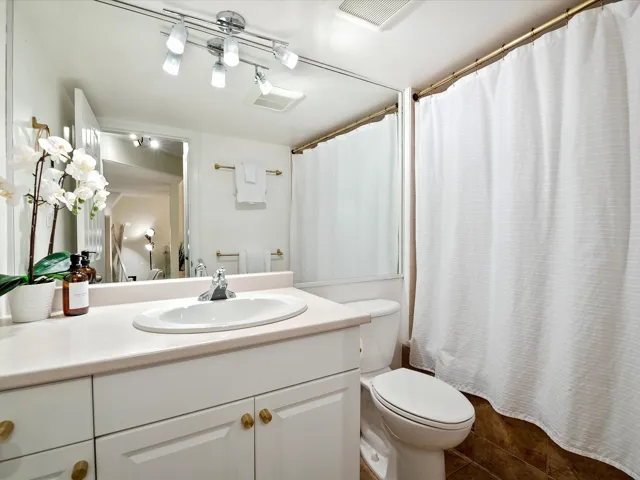 Full bathroom with tile patterned floors, toilet, vanity, a shower with curtain, and visible vents