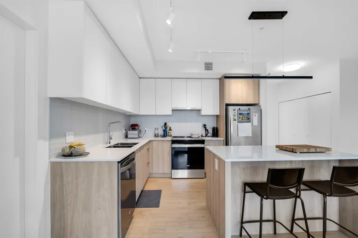Kitchen featuring appliances with stainless steel finishes, modern cabinets, decorative backsplash, and a kitchen bar