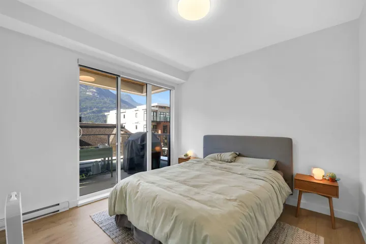 Bedroom with wood finished floors, access to exterior, a baseboard radiator, and a mountain view