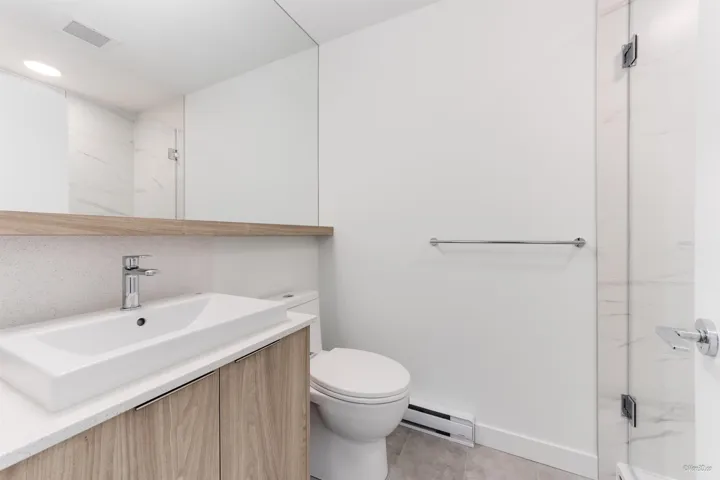 Bathroom featuring baseboard heating, a marble finish shower, and vanity