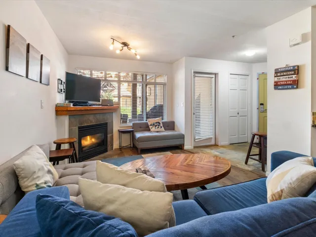 Living area with light wood finished floors, a tile fireplace, and baseboards
