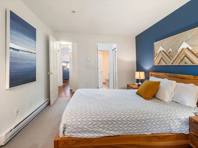 Bedroom featuring carpet flooring, arched walkways, baseboards, baseboard heating, and connected bathroom