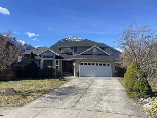 Traditional-style house featuring stucco siding, a mountain view, roof with shingles, concrete driveway, and an attached garage