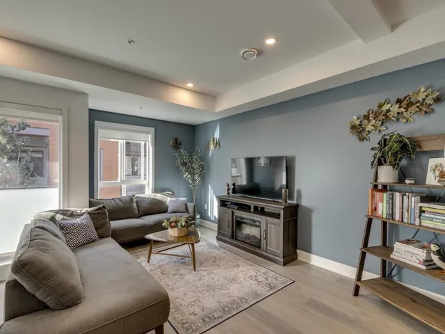 Living area featuring baseboards, a glass covered fireplace, light wood-style floors, and recessed lighting