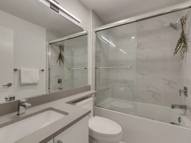 Full bathroom featuring enclosed tub / shower combo, toilet, and vanity