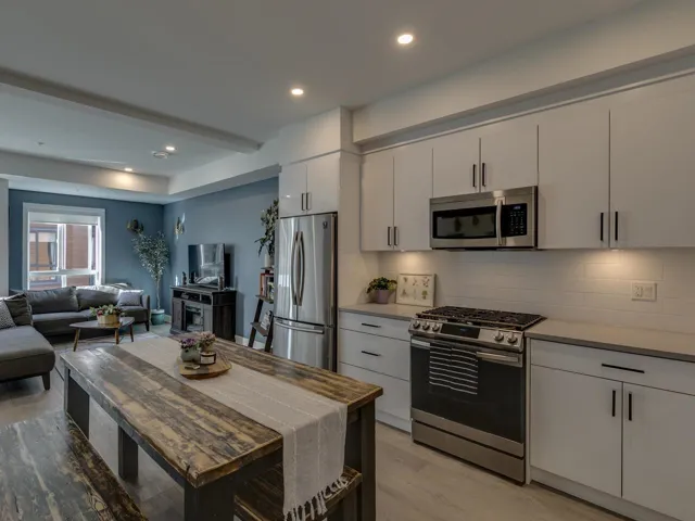 Kitchen with tasteful backsplash, open floor plan, light wood finished floors, white cabinets, and appliances with stainless steel finishes