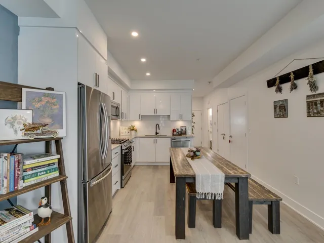 Kitchen featuring white cabinets, stainless steel appliances, a sink, and light wood finished floors
