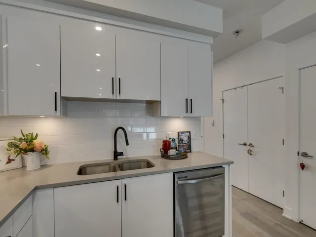 Kitchen with beverage cooler, light wood finished floors, modern cabinets, a sink, and white cabinetry