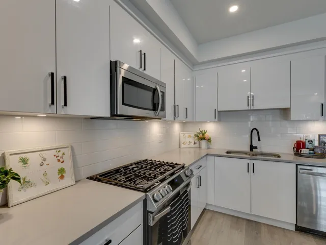 Kitchen featuring a sink, modern cabinets, white cabinets, backsplash, and appliances with stainless steel finishes