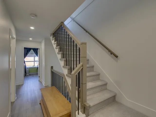 Staircase featuring baseboards, wood finished floors, and recessed lighting