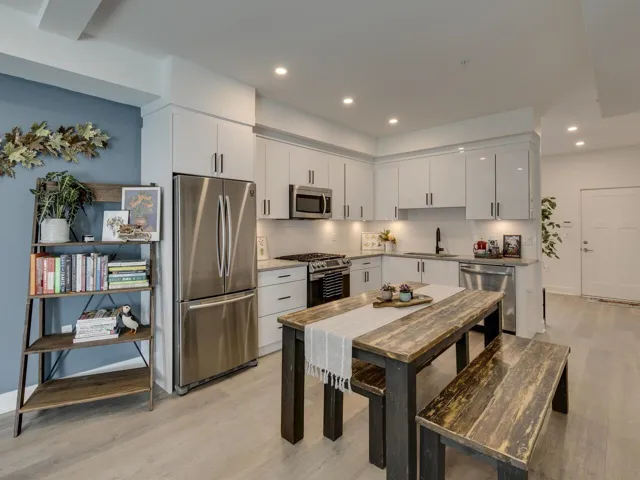 Kitchen with light wood finished floors, decorative backsplash, a sink, and appliances with stainless steel finishes