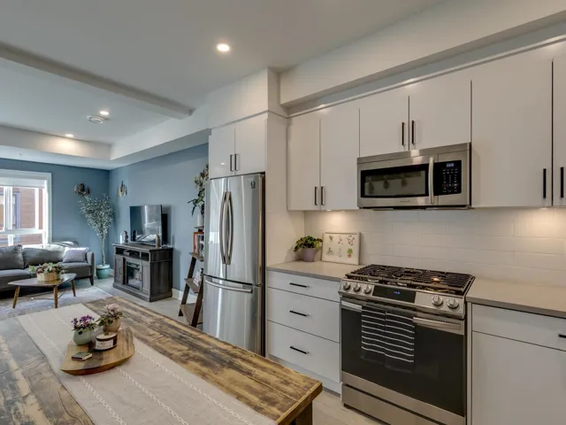 Kitchen with tasteful backsplash, open floor plan, light countertops, white cabinets, and appliances with stainless steel finishes