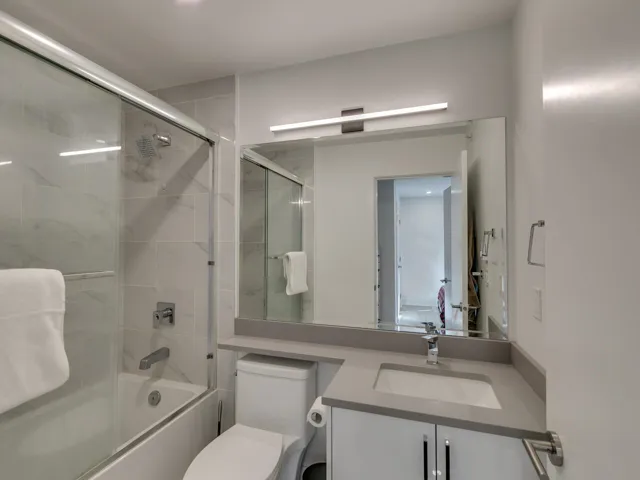 Full bathroom with combined bath / shower with glass door, toilet, and vanity