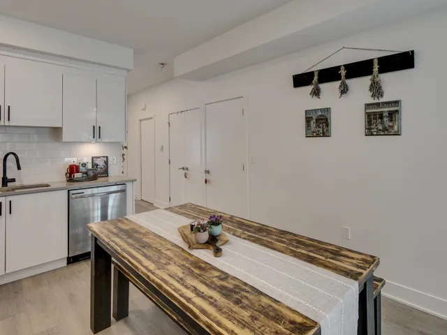 Kitchen with white cabinets, stainless steel dishwasher, light wood-style flooring, a sink, and decorative backsplash